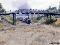 CNR U-1-f "Bullet Nose Betty" 6060 is seen on the point of an excursion run by the NRHS Buffalo Chapter from Niagara Falls to Guelph via Lynden and return, seen passing beneath the Harrisburg Road bridge and through the remains of Harrisburg Junction.  A number of fans were out chasing this day including <a href=http://www.railpictures.ca/?attachment_id=42990>Bruce Lowe during a photo runby</a> and <a href=http://www.railpictures.ca/?attachment_id=14342>Bill Thomson at CN Guelph Junction.</a><br><br>Rails were laid through Harrisburg in 1853 leading off the right of this image where <a href=https://imagery.zoogletools.com/u/131959/dffdb8c2c3fd4e8170e912d7143d9df5fa4d1a61/photo/harrisburg-gtr-1901-south-dumfries-hs.jpg>the original</a> and the <a href=https://imagery.zoogletools.com/u/131959/85c61fb90e20a77bb2e0b7f880c6356d4ae2a840/photo/harrisburg-cnr-ex-gtr.jpg>circa 1906 stations</a> once sat on the former Great Western Railway Niagara Falls - Hamilton - London - Windsor mainline, on which service commenced in January 1854.  Located 3.13 miles west of Lynden, Harrisburg is considered the first railway junction in Canada, as the Great Western Railway built a branch north to Galt via Branchton opening on August 23, 1854.  West of Harrisburg, the mainline passed just south of St. George before <a href=https://images.ourontario.ca/Partners/cbpl/CBPL063835f.jpg>crossing the Buffalo, Brantford & Goderich Railway at Paris Junction (1856).</a>  Brantford did not receive service from the GWR until 1871 via a branch line (later CN Alford and Dundas Subdivisions).  After amalgamation with the Grand Trunk on August 12, 1882, the GTR worked to provide the area with better service as well as increase their profits resulting in the Lynden cutoff being constructed from <a href=https://imagery.zoogletools.com/u/131959/22ac57c264132f2e674b4a41633bc7cb2b73bb7c/photo/lynden-jct-gtr-lk-east.jpg>Lynden (Junction)</a> to join the Alford Branch (Alford Jct. – south of Powerline Road crossing).  With the new mainline in service the Alford Sub would be abandoned in 1924, and the GWR mainline west of St. George to Paris Junction (Harrisburg - Paris Jct. renamed St. George Subdivision) abandoned in 1935.  The remainder of the St. George Sub would be abandoned in 1962, leaving the former Galt Branch, now the Fergus Sub, as the only active rail through Harrisburg for another couple decades.  Eventually though it too would be abandoned from mile 1.00 Lynden Junction to mile 13.88 at Galt in 1986, the last revenue carload having passed over the line in 1979.  Today almost a mile of double tracked rusted rail remains in the weeds severed from the Dundas Sub as a reminder of the old mainline.<br><br>On a lighter note the Great western was a pioneer of sorts in North American rail transportation, as beginning in January 1854 the GWR would be the first North American Railway to operate <a href=https://www.trha.ca/trha/wp-content/uploads/2019/02/GWRFirstRPO1854.jpg>travelling Railway Post Office cars</a> which would provide revenue to many of the branch lines and local trains for over a century until the end of RPO service on April 24, 1971.  Further details provided in this interesting article on Canadian RPO car operations by <a href=https://www.strathroyagedispatch.com/news/local-news/former-mail-clerk-remembers-the-canadian-railway-mail-service>former RPO Clerk, Norm Giffen.</a><br><br>More Harrisburg:<br>Bill Thomson: September 20, 1970, <a href=http://www.railpictures.ca/?attachment_id=26290>CNR 6218 southbound</a> with her <a href=http://www.railpictures.ca/?attachment_id=26348>fireman keeping watch.</a>