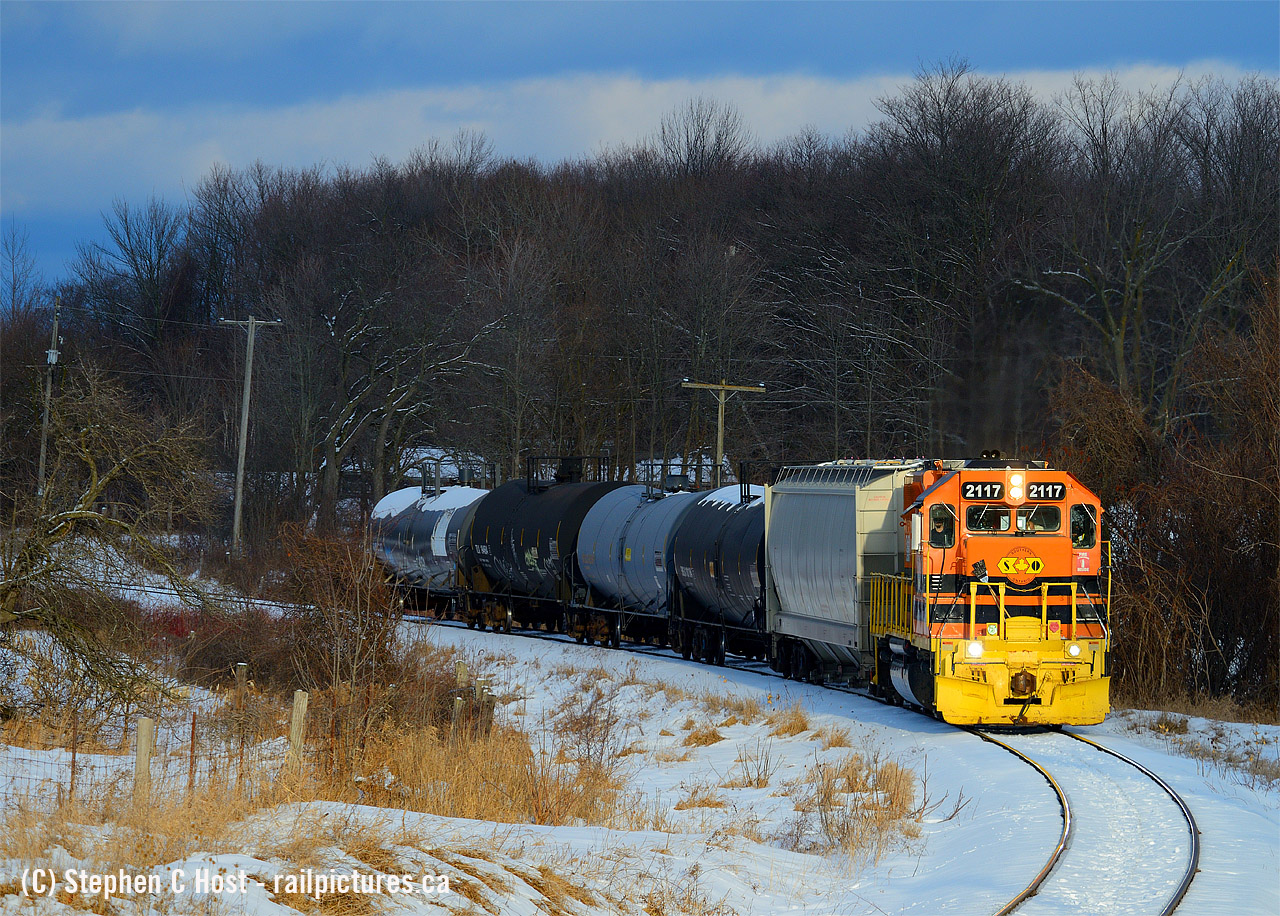 On a late January afternoon I found myself following GEXR 583 northward on the Guelph Junction Railway with clouds to the south, and pure setting sun to the north creating magnificent lighting conditions. 2117 is working hard with five cars as this is one of the good northward grades on GJR. The train is approaching what the railroaders call Danger Bell, known as such due to the angle of the road/rail crossing, poor visibility and naturally the potential for accidents. In recent years a Crossbuck had been replaced with flashers and lights to help improve safety.