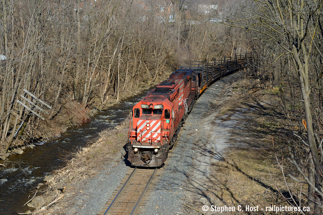 Leading a rail train, a pair of old soldiers rolls downgrade along the Grindstone Creek in Waterdown where a telegraph pole hangs precariously in the balance. I wonder if flooding or washouts has been an issue for the CP along here given how close that water is to the right of way.