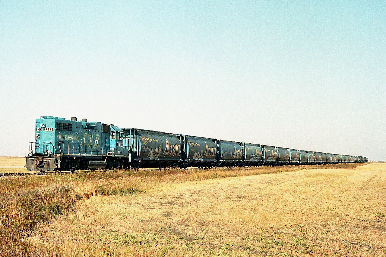 Sure not much to see along the Stewart Southern line S/E of Regina. Just fields. And an equally nondescript train rolling along. Not sure of the speed limit, but it appeared 15MPH. GMTX 2213, lettered for the Stewart Southern, has a short train, a grouping of "Alberta" grain hoppers and a few tanks on the end.