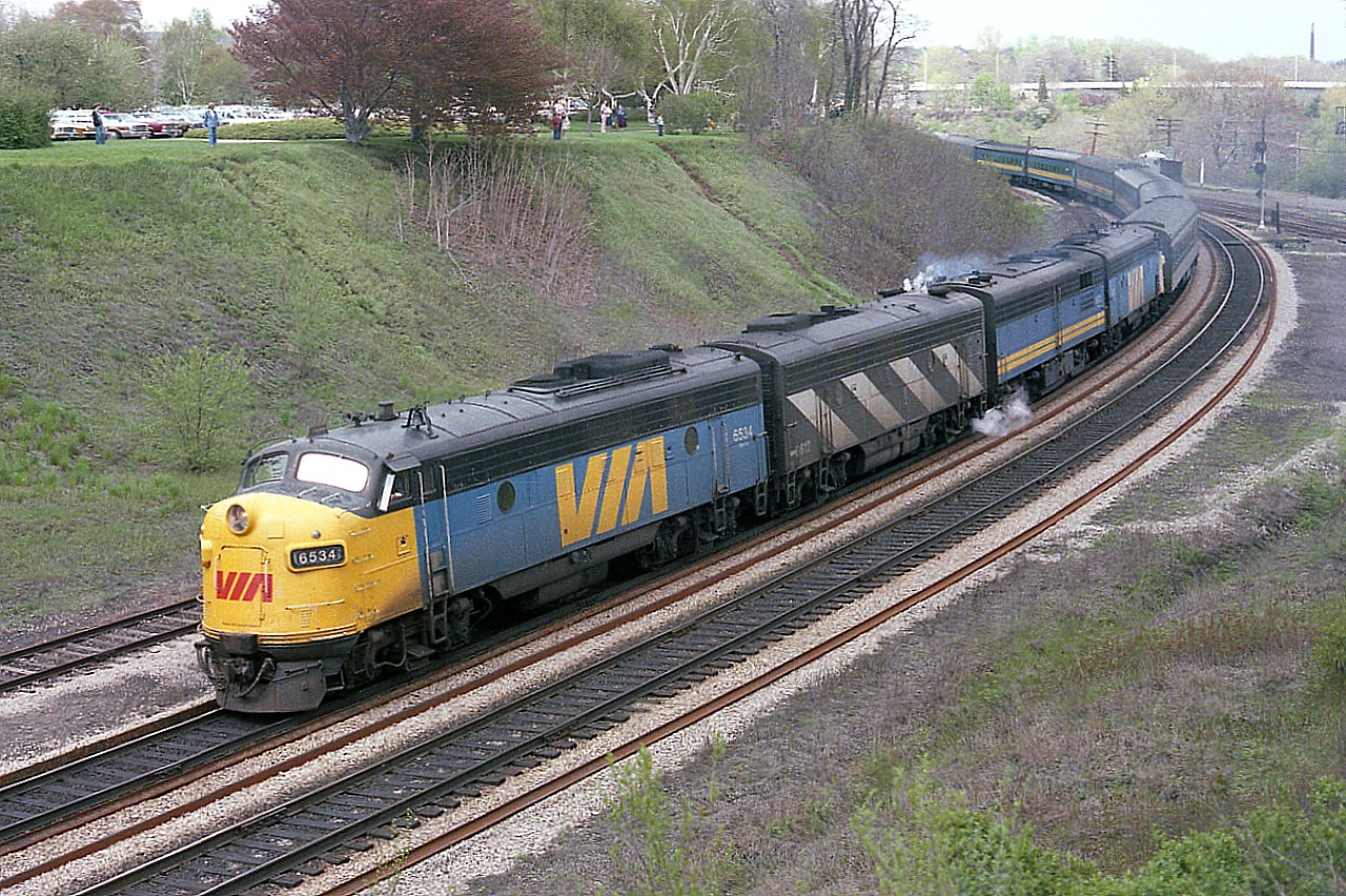This was a typical Sunday night at Bayview Junction some 40 years back;taking in the enjoyment of watching impressive passenger trains snake their way up and down the line.  Typical in this time frame is #75, shown here, westward, with VIA 6534, 6612, 6870 and 6516 and 18 coaches; a period when passenger trains really looked like passenger trains. It is a shame how the service has been neglected, chopped up by various governments and incompetent management. Note that, compared to today; the hillside is clear, there is little trash; the parking lot is full as once it was free to come and enjoy the parkland settings your taxes paid for.  This was a wonderful area to enjoy the sweet light of the evening....back then.
