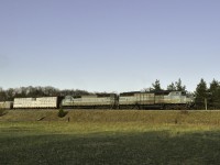 In the dying spring light CMQ 9020 and 9011 lead GPS-16 as they lug it up the grade south of Tottenham. Photographing trains is something I wish I could do more often. I adventure out so infrequently that I can just barely call it a hobby. I am out so little that the last time I saw an SD40 of any kind was close to 7 years ago, just as CP began to purge much of their fleet. So, when I caught wind that 2 blue barns would be leading it was trackside I went. Soon a distant cry of a Nathan K3L rang off the shallow valley walls, and not long after the echo of 645s approached. A headlight crested the small hill and 2 of GMDs finest made their presence known. With mixed freight and a loaded ballast train in tow, they are down to about 10 miles an hour. While the glory days of fast freight and priority trains may be over for these old soldiers, they now earn their keep on the trains that keep the railroad running.