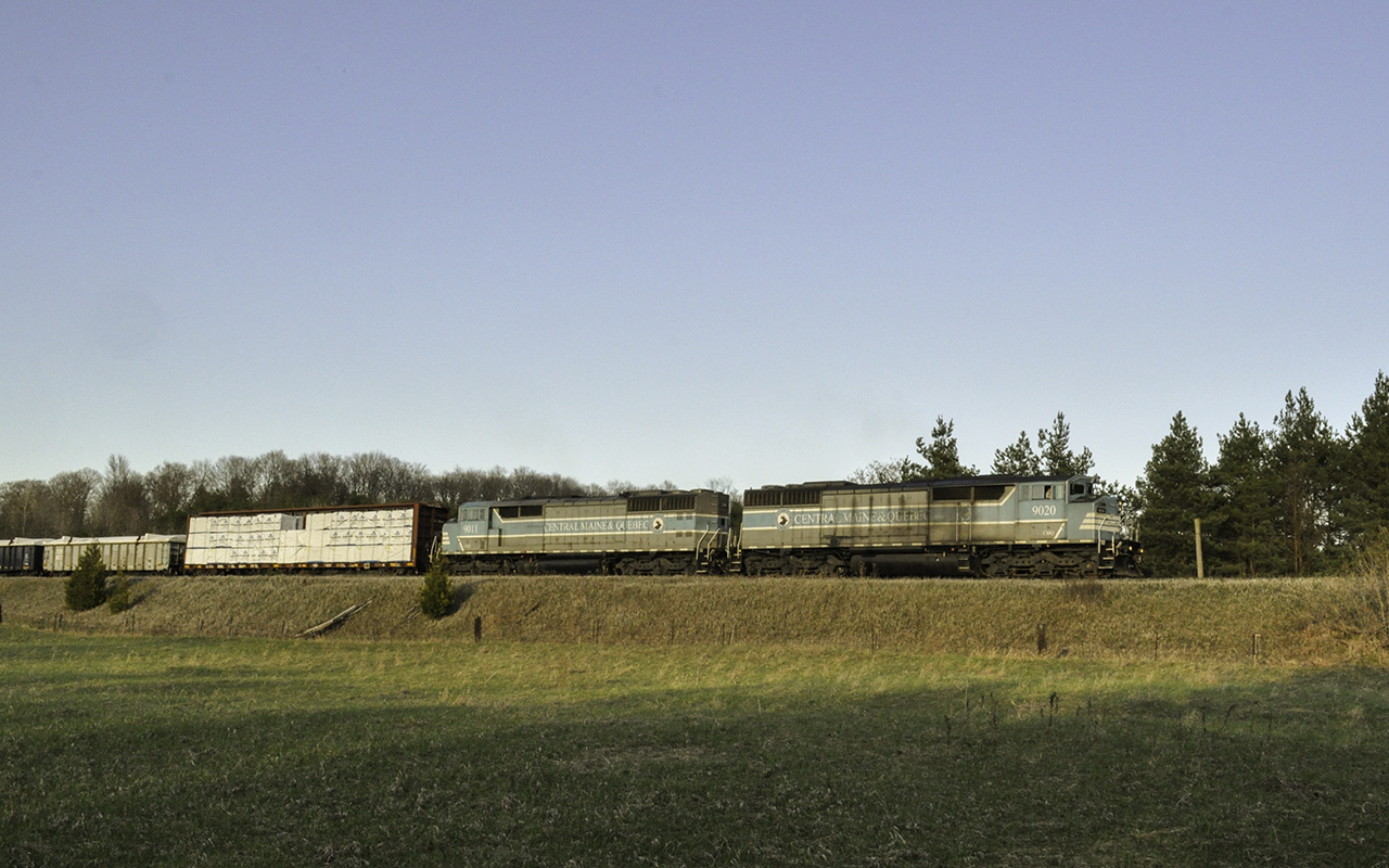 In the dying spring light CMQ 9020 and 9011 lead GPS-16 as they lug it up the grade south of Tottenham. Photographing trains is something I wish I could do more often. I adventure out so infrequently that I can just barely call it a hobby. I am out so little that the last time I saw an SD40 of any kind was close to 7 years ago, just as CP began to purge much of their fleet. So, when I caught wind that 2 blue barns would be leading it was trackside I went. Soon a distant cry of a Nathan K3L rang off the shallow valley walls, and not long after the echo of 645s approached. A headlight crested the small hill and 2 of GMDs finest made their presence known. With mixed freight and a loaded ballast train in tow, they are down to about 10 miles an hour. While the glory days of fast freight and priority trains may be over for these old soldiers, they now earn their keep on the trains that keep the railroad running.