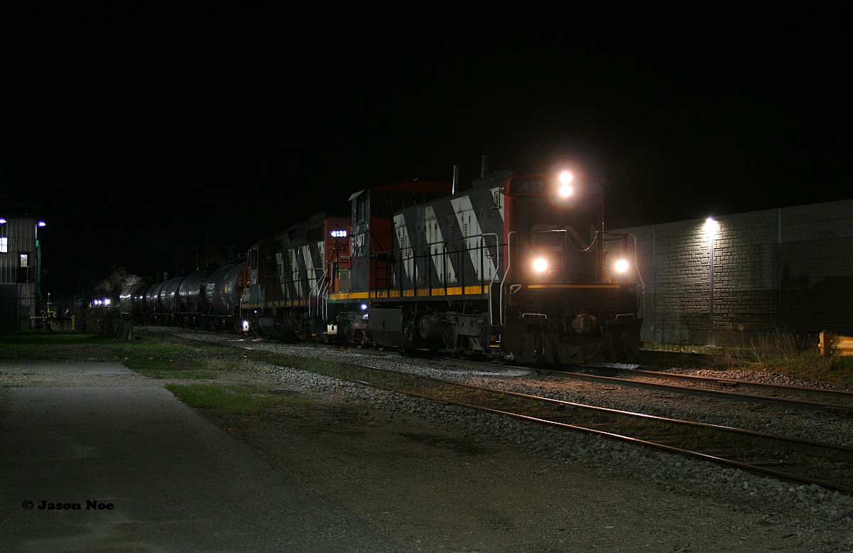 After photographing CN 1439 working Hamilton during March I figured that was likely the last GMD-1 I would photograph as it was the only one remaining in active service in Ontario. This had followed the news that CN had retired all of its Ontario assigned GMD-1’s earlier the same month. And while photos emerged of them still idling away and seemingly still being kept in operating condition at MacMillan Yard, the likelihood of retired units on CN receiving a second chance at service didn’t seem all that plausible. 

Then on April 21, a photo of CN 1437 surfaced at Kitchener having been set-off by 533 at the yard hours prior. While speculation swirled about the circumstances of this, the reality was CN L540 began using it to switch the yard along with CN 4131 later that afternoon. Then that same night, CN L566 was assigned 1437 and 4131 and headed north to Elmira on the Waterloo Spur with three tankers. Having just missed the train in Uptown Waterloo at 23:15 I was left with a simple choice of going home to bed or continuing the pursuit to Elmira where the only other photos were possible. I mean how often does one get to chase a retired GMD-1 in the dark….as logically this really shouldn’t even be happening in the first place.

Elmira is an extremely quiet place at night. Even with both chemical  companies purring away the wee hours of the new day, the only sounds heard while I waited for 566 to complete its first set of switching moves, were the flags outside the Lanxess facility flapping impatiently in the chilly night air. Finally at 01:00, 1437’s headlights began inching closer and eventually L566 came to stop beside the Lanxess plant as the crew prepared to uncouple the power and run-around their tankers. With my tripod set-up I clicked away in the darkness hoping to get something as this was the last opportunity to get 1437 leading before it would be coupled to waiting cars at Lanxess. I had time for just four exposures, one seen here, before the crew would runaround and switch ends to 4131, which would lead L566 back to Kitchener. 

The following night on April 23, CN L566 set-off 1437 in St. Jacobs on their next trip north to Elmira and that same day the Waterloo Central Railway had officially announced that CN had graciously donated the retired but still operational GMD-1 to the organization. While now officially off the CN roster, 1437 has a bright future ahead as it enjoys retirement no longer moving freight, instead future passengers on a spur it can now say it had led its final CN train over.
