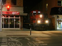 CN GP9RM 7038 solely leads L566 through Uptown Waterloo approaching King Street just before midnight as it heads to Elmira on the Waterloo Spur.