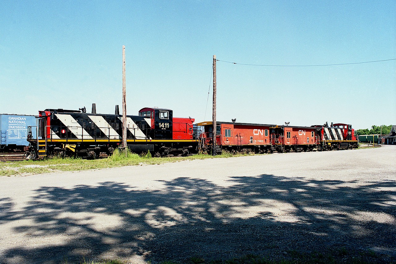 So I am hearing most of the GMD-1u switchers are going into storage. Its a shame. They were great little engines and most of us will miss them.
Here is a shot of back 30 years time when a pair of them were stationed at Merritton Yard, which connected with the Grimsby sub at mile 9.5; now part of the the GIO Trillium outfit.
From left, CN 1411, transfer vans 76602, 76547 and CN 1413. The yard has since been taken up as operation was transferred to 'PCHR' (now GIO Trillium) back around late 1999. The old Merritton station can be seen at the mainline connection at the extreme right in the photo.  Arsonists burned the station down in Oct 1994. CN 1411 was retired, 2006; 1413 went to Oregon Pacific in 2007. Don't know about the transfer vans; CTG indicates only 3 left out of 210)
(I realize it is inevitable with the passage of time, but all these shortline name changes drive me nuts)