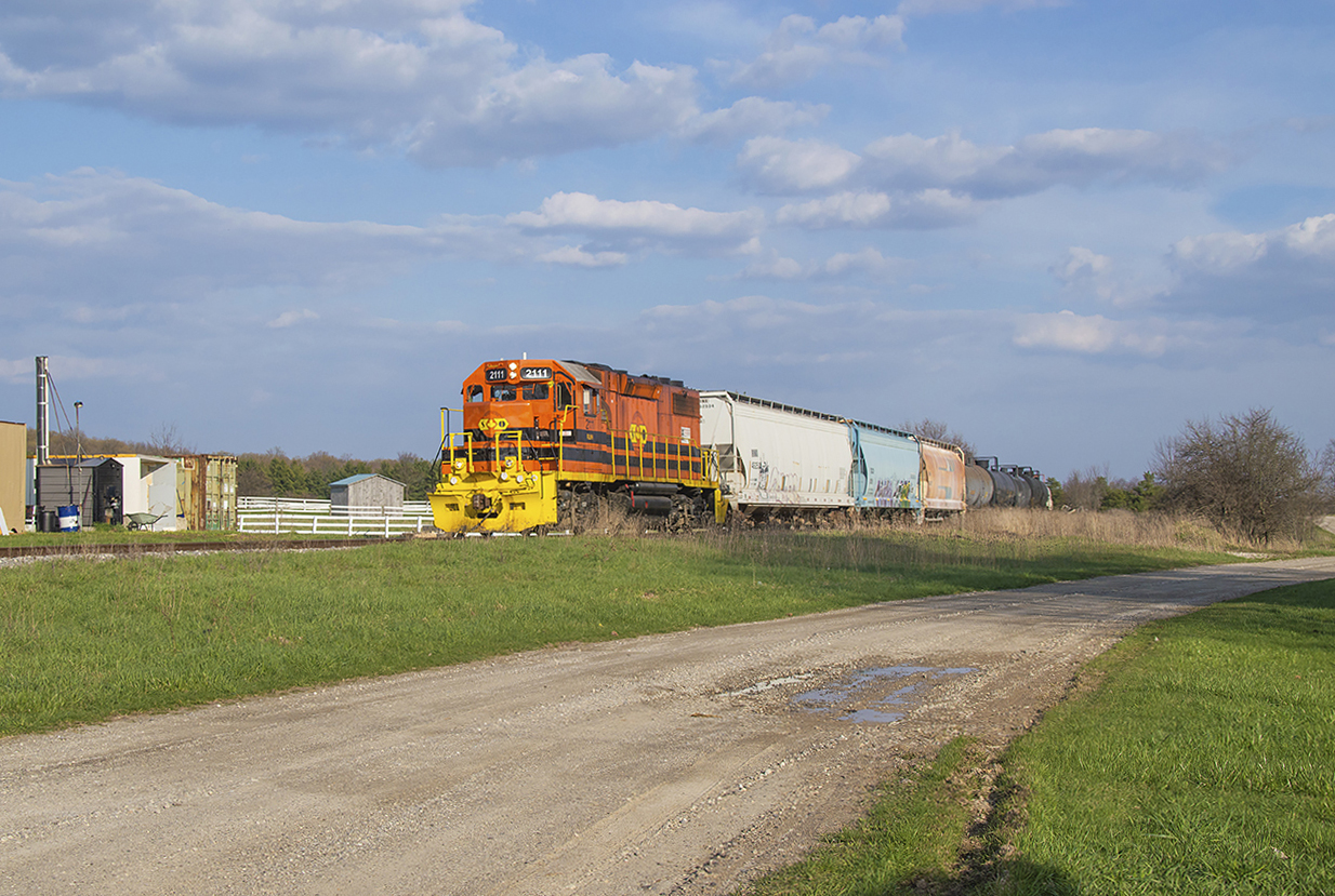 GEXR 583 is seen trundling northbound from Guelph Junction with traffic for PDI and a car for Owens Corning Fiberglass third up passing through the hamlet of Corwhin at 1816h.While Corwhin developed largely around the Guelph Junction Railway, its early years took place about 1 kilometer east of the rail line at the intersection of Wellington Road 34 and Nassagaweya-Puslinch Townline, right on the Puslinch and Halton border. The mid 1800s saw numerous settlers come to the area and the settlement of Corwhin was one of many nearby. It consisted of a church, blacksmith shop, and post office, though the village had never prospered as the only route to town involved a poorly built swampy road. The building of the GJR in 1887 changed that with reliable transportation to the area, leading to the post office and general store being moved closer to the railway. Under CPR operations the railway built a small station (a second being built circa 1911), used by high school students headed to Guelph, in addition to a house for the local section foreman, and a couple of sidings for use by the nearby coal yard and stock pens.*Despite having a number of trips each day, Saturday, August 4, 1962 saw the end of passenger service on the GJR and as the station was no longer needed it was moved to a farm owned by Ontario's Provincial Secretary, John Yaremko. For a number of years passenger service was operated using a battery car, often CPR 9002, nicknamed "Old Sparky" by residents along the line. Sparky would be replaced by a gas-electric doodlebug, usually CPR 9004, in the 1940s until 1958 when steam powered mixed trains would take over the passenger service for its final years.*Information from Puslinch Historical Society
