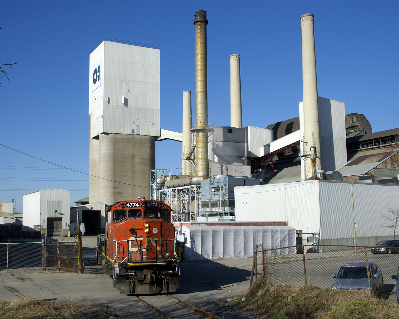 The Point St-Charles Switcher is backing into the O-I plant, where it will spot a loaded car and lift an empty car. CN accesses this client via the Butler Spur and then briefly going through the VIA Rail Montreal Maintenance Centre.