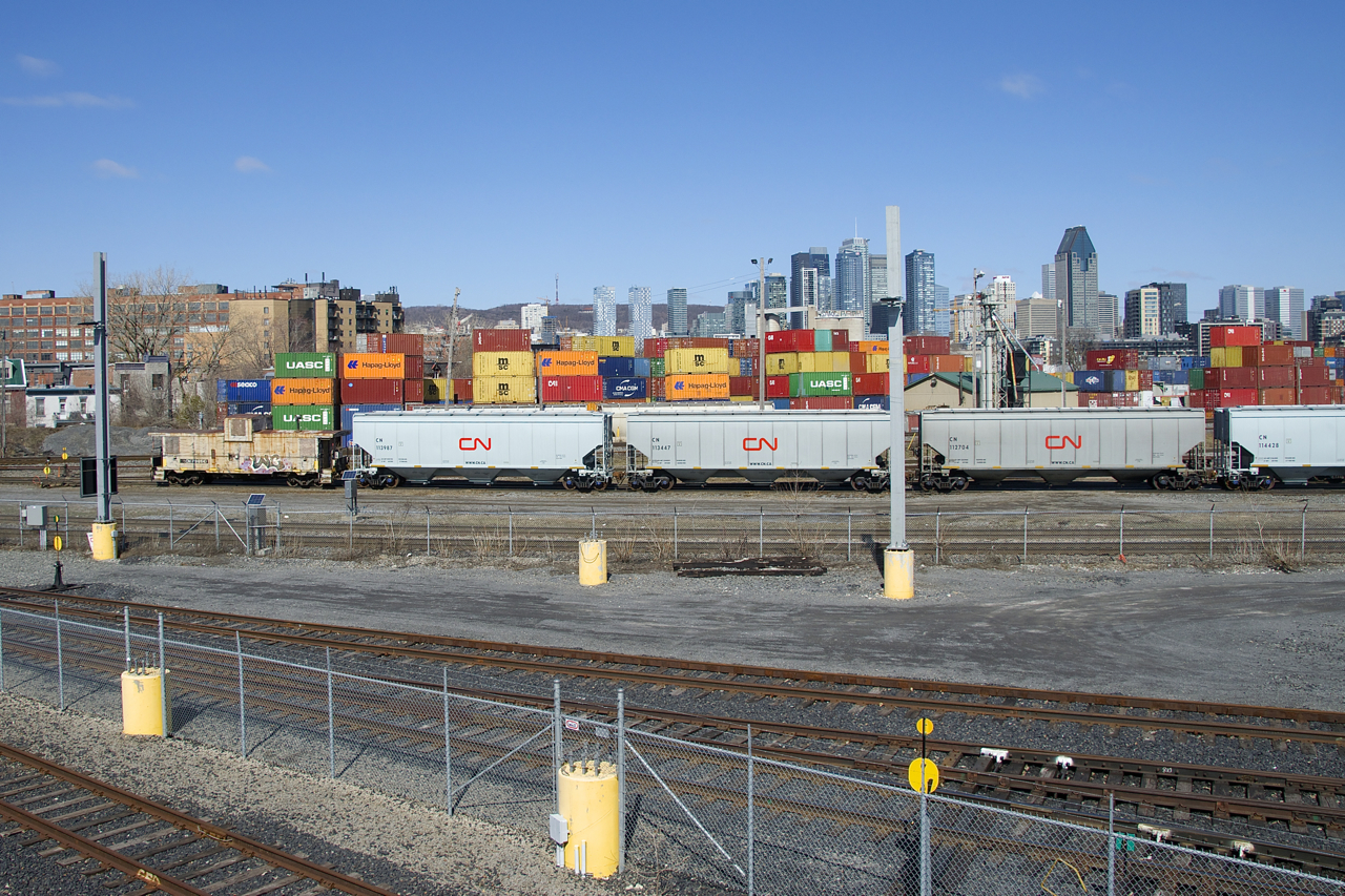 The beat up caboose and the new hoppers at the tail end of the Pointe St-Charles switcher provide quite a difference in appearance as they enter the yard with grain empties.
