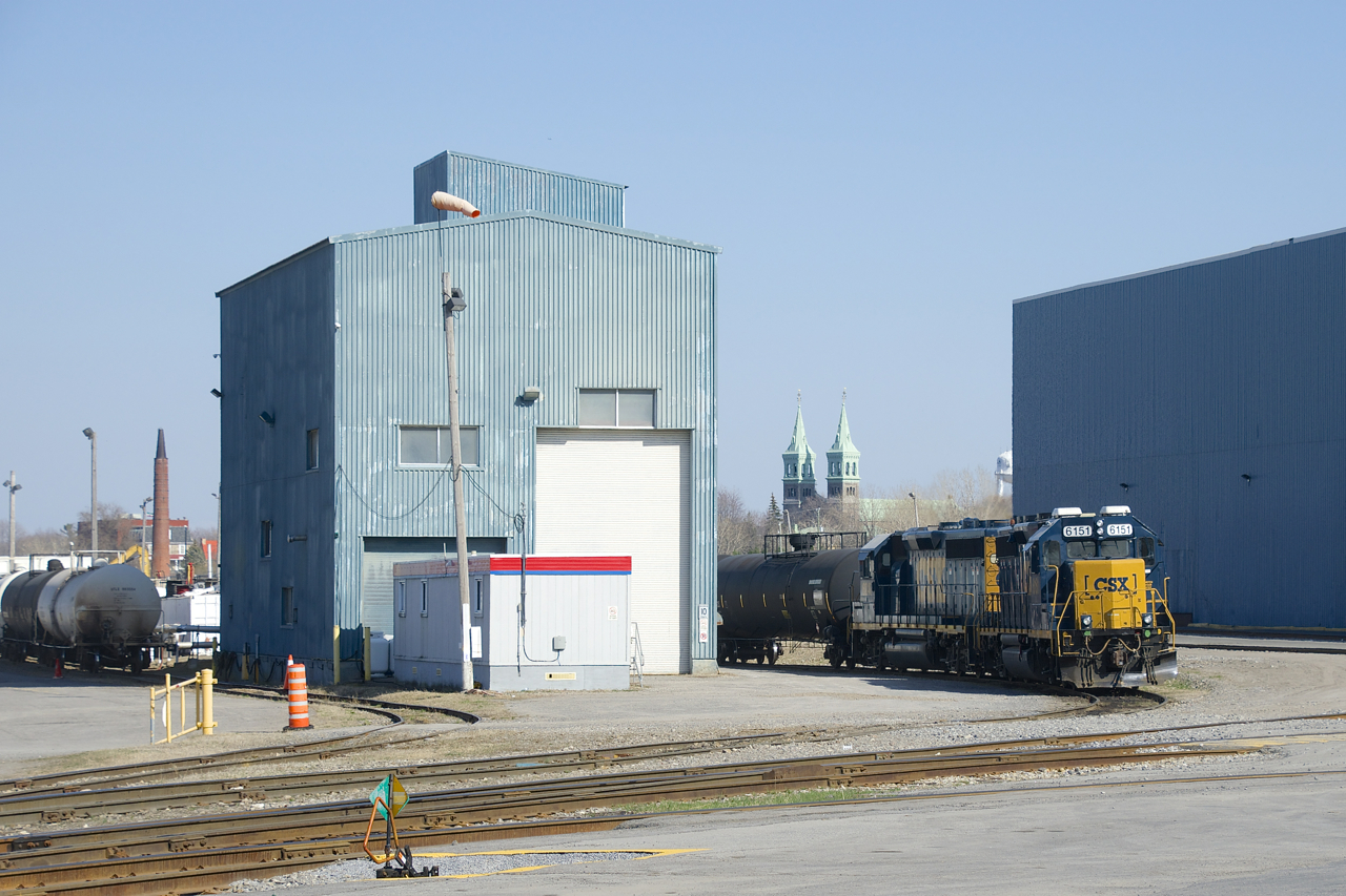 The local power is at rest in the Transflo yard in Beauharnois on a warm Saturday afternoon. In the background at right is the St-Clément Catholic church, which was completed in 1845. At left is the smokestack of what remains of the Spexel paper mill. Built in 1912, It closed in 2004 and was demolished in 2020 after a fire damaged it. It produced Canadian currency for numerous decades.