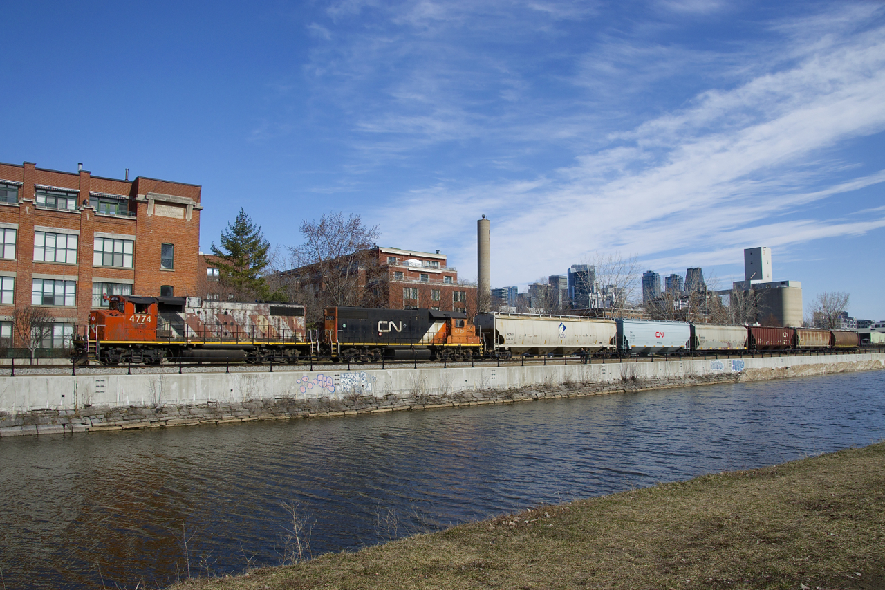 After lifting grain empties from Ardent Mills and putting them in a siding, the Point St-Charles Switcher is shoving loads towards the mill, visible at far right. The smokestack in the middle was part of a Stelco factory that once operated here.