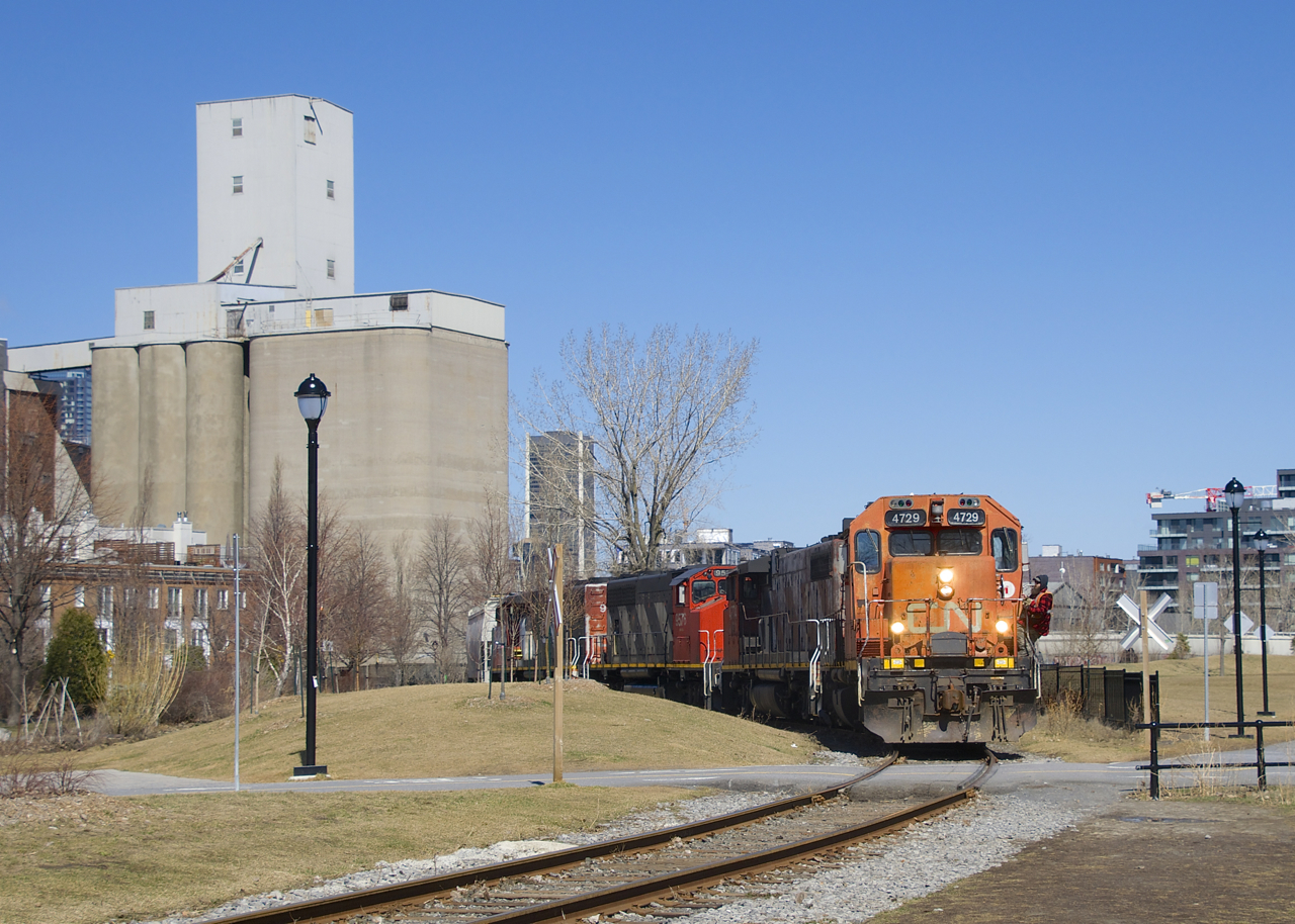 A crewmember is about to flag a fairly new pedestrian crossing as the Pointe St-Charles Switcher does some moves at Ardent Mills as they pick up grain empties.