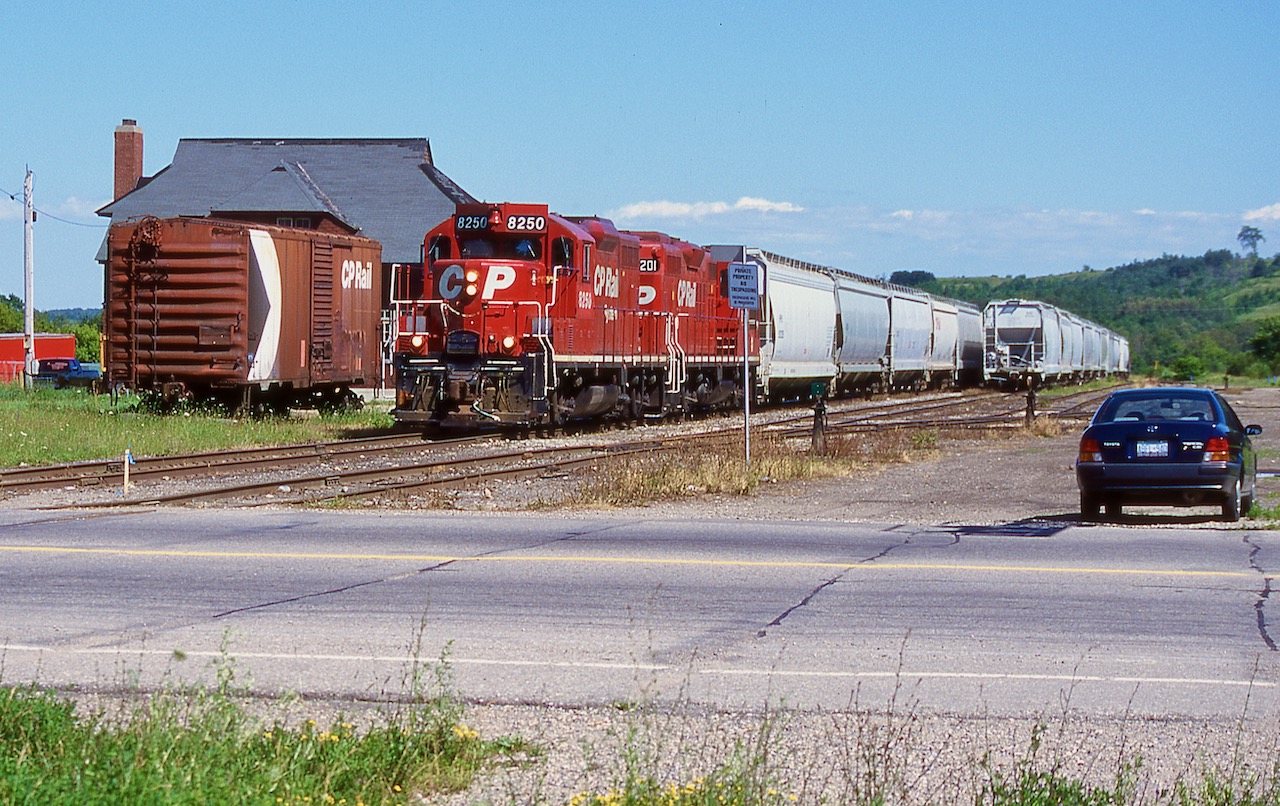 Nearing the end of CP's ownership of the Owen Sound Subdivision I decided to make one last trip to Orangeville. This time I was rewarded with a pair of repainted GP9U's, from almost the top and bottom of the 8200's list. The train has just arrived in town and is beginning to work the relatively full yard. My old Tercel sits to the right as a photo prop. The bunk house and boxcar would survive the OBRY takeover but are both long gone today. The old 40' boxcar sits where the old station once sat, and there was once a run around track located behind it. Today the station sits near downtown and is a popular restaurant.