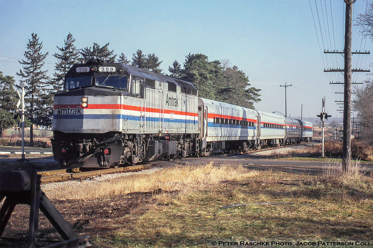 Its been 17 years since the final run of the Amtrak/VIA Toronto – Chicago International on Friday, April 23, 2004.  Here the westbound 685 is seen crossing Mill Street in Baden on the run to Chicago.  At this time the train had been running over the Guelph subdivision for less than a year, having been shifted to the north mainline from the Oakville/Dundas subs on January 15, 1990.  F40PH 359 (built Dec. 1980) leads this day’s train made up of mostly Horizon cars plus one Amfleet I coach.  Note the second car wears the narrow stripe phase iii scheme while the others wear the wide stripe phase iii scheme.  While the 359 is long gone from Amtrak’s roster the Horizon and Amfleet cars still make up much of the fleet.More Amtrak International on the Guelph Sub:Stratford, June 16, 2000 by Arnold MooneyGuelph, October 2000 by Bill ThomsonKitchener, April 13, 2004 by Steve HostPeter Raschke Photo, Jacob Patterson Collection slide.