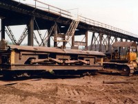 Below the Charging Deck, Blast Furnace raw materials Iron, Coke, and Fluxing agents are stored in the Stock House where these materials are gravity fed to custom built <Scale Cars> which in turn fed inclined skip carrying cars that ultimately charge the Blast Furnace Top.  What you are seeing here is one of the <Scale Cars> that was removed from the Stock House during plant demolition.  The units were standard track gauge, all riveted construction, and designed as side discharge (visible) to the skip carrying cars.  In behind the <Scale Car> is the Iron Trestle used to access the Charging Deck, first with 0-4-0 steam locomotives (1913-1941), then the short-lived Davenports (1941-1949), and finally GE 50 Ton Center Cab units until plant operations closed (March 1977, but one of the two GE 50 Ton units were on site and active until the later half of 1981).  