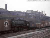 With stack capped and rods removed, CNR P-5-f, 0-8-0 switcher, 8360 (MLW, May 1929) is viewed bound for the scrappers torch (September 1961), presumably at London, in transit amongst numerous cars off the American roads including a wooden Great Northern boxcar, Chicago & North Western gondola, a Pennsy box, and reefers from the Atchison, Topeka & Santa Fe.  8360 had been based in the Ottawa area per a 1957 assignments list.  Moving through what would today be <a href=http://www.railpictures.ca/?attachment_id=20392>Exhibition GO station,</a> the neighbourhood has been gentrified over the last few decades with Inglis being one of the casualties.<br><br>Founded in 1859 by Thomas Mair, John Inglis, and Francis Evatt on July 27, 1859, John Inglis and Comapny began as a small machine shop under the name Mair, Inglis, and Evatt in Guelph producing milling machinery before moving to the Strachan Avenue location in Toronto in 1881 becoming John Inglis and Sons.  Renamed many times, it was last changed to Whirlpool Canada in 2001. The famous blue and white billboard overlooking the Gardiner Expressway would go up in 1975 with many messages displayed to motorists over the years, and would be dimmed and demolished during the last week of July, 2014.  More info found under Bruce Lowe's shot below.<br><br>More CNR 0-8-0 switchers:<br><a href=http://www.railpictures.ca/?attachment_id=39626>P-5-a 8304 at Hamilton,</a> Doug Page, 1960<br><a href=http://www.railpictures.ca/?attachment_id=15641>P-5-j 8421 at Spadina Coach Yard,</a> Bill Thomson, 1958<br><a href=http://www.railpictures.ca/?attachment_id=37810>P-4-b 8438 at Bathurst Street Yard,</a> Bill Thomson, 1958.<br><br>More Inglis:<br><a href=http://www.railpictures.ca/?attachment_id=18366>Facing the other direction,</a> Tony Bock, 1978.<br><a href=http://www.railpictures.ca/?attachment_id=43811>Eastbound doubleheader,</a> Bruce Lowe, 1955.<br><a href=http://www.railpictures.ca/?attachment_id=11861>The Inglis sign,</a> hodgsontoaylen, 2004.