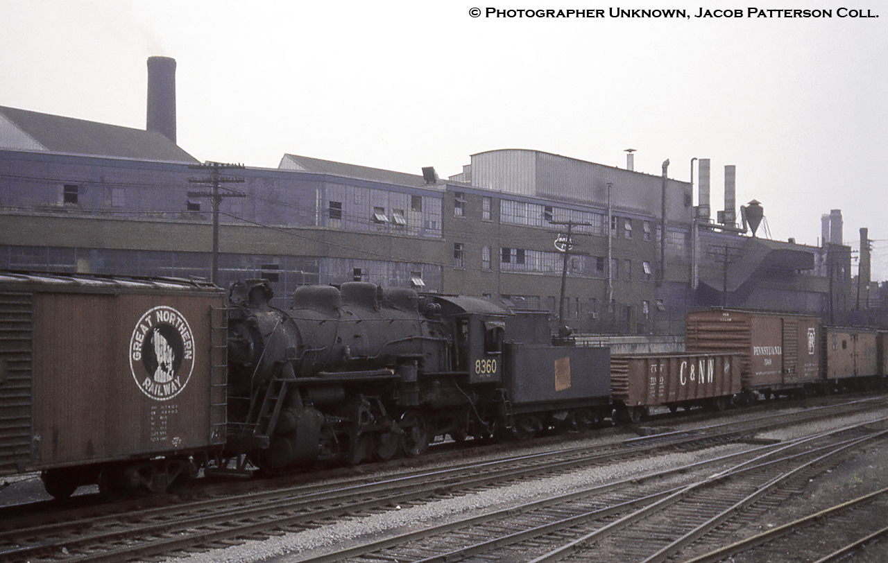 With stack capped and rods removed, CNR P-5-f, 0-8-0 switcher, 8360 (MLW, May 1929) is viewed bound for the scrappers torch (September 1961), presumably at London, in transit amongst numerous cars off the American roads including a wooden Great Northern boxcar, Chicago & North Western gondola, a Pennsy box, and reefers from the Atchison, Topeka & Santa Fe.  8360 had been based in the Ottawa area per a 1957 assignments list.  Moving through what would today be Exhibition GO station, the neighbourhood has been gentrified over the last few decades with Inglis being one of the casualties.Founded in 1859 by Thomas Mair, John Inglis, and Francis Evatt on July 27, 1859, John Inglis and Comapny began as a small machine shop under the name Mair, Inglis, and Evatt in Guelph producing milling machinery before moving to the Strachan Avenue location in Toronto in 1881 becoming John Inglis and Sons.  Renamed many times, it was last changed to Whirlpool Canada in 2001. The famous blue and white billboard overlooking the Gardiner Expressway would go up in 1975 with many messages displayed to motorists over the years, and would be dimmed and demolished during the last week of July, 2014.  More info found under Bruce Lowe's shot below.More CNR 0-8-0 switchers:P-5-a 8304 at Hamilton, Doug Page, 1960P-5-j 8421 at Spadina Coach Yard, Bill Thomson, 1958P-4-b 8438 at Bathurst Street Yard, Bill Thomson, 1958.More Inglis:Facing the other direction, Tony Bock, 1978.Eastbound doubleheader, Bruce Lowe, 1955.The Inglis sign, hodgsontoaylen, 2004.
