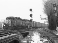 <br>
<br>
   In the light snow
<br>
<br>
    two SD40's at Leaside Junction,
<br>
<br>
   CP Rail SD40-2  # 5749  west with SD40 #5539, have grain empties in tow
<br>
<br>
   on the left mile is 0.2 North Toronto Sub, on the right is the Don Branch mile 206.4 Belleville Sub.,
<br>
<br>
   note the  'return-to-train'  push buttons near the base of each signal mast to allow crews to have a 'restricting' signal for each route ( to accommodate 'the push' engine(s) ).
<br>
<br>
   the phone in the phone box at the base of the 0.2 mile signal mast is active.
<br>
<br>
   And at the near right was the newly lifted siding switch into the Caterpillar dealership
<br>
<br>
   and jointed rail everywhere !
<br>
<br>
   at Leaside Junction, Kodak Tri X negative, December 22, 1979 by S.Danko
