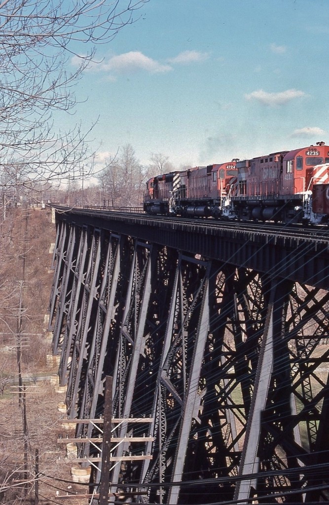 The CPR bridges * over the West Don River ravine - the image demonstrates the challenges of Lake Ontario north shore railway construction.  


  And yes, bridges, in plural, look closely, the near (north track ) bridge accommodated % the Canadian Northern Railway only access to Leaside where the main CNoR locomotive # and car shops were constructed. 


  The south track bridge is younger, being a replacement of the original 1884 bridge built by the CPR controlled Ontario & Quebec Railway . 
    

  Soaring over the E. T. Seton Park, on approach to the Don Mills crossover a ubiquitous SD40 and two MLW  4726 – 4235  in charge of an eastbound CP Rail, January 12, 1980 Kodachrome by S.Danko.


  What's interesting:


   *   The CPR controlled O & Q Railway survey crews located the new line ( circa1882 ) where the Don River  ravines  were the narrowest, in the area of the John Lea family farm. First O & Q  through train Parkdale to Peterborough June 28, 1884, via West Toronto (Junction) and North Toronto stations (Yonge St). The Don River branch was completed 1893.
 

    %   About 1910 the CNoR negotiated the use of the O & Q Railway from the Donlands Junction ( the CN Leaside branch from Duncan (CN Oriole on the CN ( ex CNoR) Bala Sub)) to Wickstead just east of CP Leaside, that 'joint section' included the north track bridge in the image. Today the O & Q is the CPR North Toronto Sub, Belleville Sub (to Agincourt), then the Havelock Sub  eastward through Peterborough, Havelock  to Glen Tay., The 93 miles east of Havelock pulled up between 1971 and 1988.


     #  The CNoR was late to the railway scene in the Toronto area. The CNoR required maintenance facilities and the only land available was the area that is now Leaside. In 1912 CNoR  purchased 100 acres, had an architect design a 'planned community' then sold off most of the land at a profit. The CNoR proceeded to build  the  CNoR locomotive shop, a roundhouse and ancillary buildings – all completed circa 1918. In 1917 the CNoR was bankrupt and in the national interest was taken over by the Canadian Government who in 1923 transferred CNoR assets to the newly created CNR. A mere 13 years after completion of the CNoR Leaside facilities, in 1930 the CNR moved most rail maintenance work out of Leaside.   The ex CNoR locomotive ( & car ) shop, a 12 railway stall building (92 x 46 meters ),  is now commercial space, occupied by a Longo's supermarket. Other evidence of CNoR railway infrastructure is long erased (there were up to 5 large buildings)...however the depressed parking lot on the east side of the former locomotive shop was the site of the CNorR's large transfer table which operated the length ( 92 metres) of the loco shop. The 10 stall roundhouse was located to the south of the loco shop and the main rail yard was east of these facilities.  One other CNoR building exists on the south side of Esandar Drive, a small structure that was the CNoR stores building and is now an automobile repair shop. 


  sdfourty