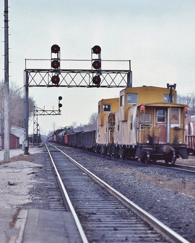 Westbound at Leaside Junction circa 1980


   ….' double tailed ' end of train devices...with CP Rail van 434337 holding the markers


   The original Leaside Junction consisted of one crossover to accommodate north track access to the Don Branch to/from the east.


   The Don Branch, to the left, commenced just beyond the second signal gantry, the south side storage tracks just west of the Don Branch switch.


   Beside the active dispatcher phone box, at the base of each of the gantry supports is the  'return-to-train'  push buttons to allow crews to have a 'restricting' signal for the respective route ( to accommodate 'the push' engine(s) ).


   At mile 206.3 CP Rail Belleville Subdivision, January 12, 1980 Kodachrome by S.Danko


   Interesting:  In the extreme foreground is part of the VIA era passenger kiosk platform. The west end of the steam era centre platform, between the south and north man tracks, extended almost a half mile well to the east of the existing former Leaside station building, commenced immediately to the right of the camera location. The centre platform was removed in the early 1980's at the time the welded rail installed.


   More Leaside


     Budds'     


    eastward view