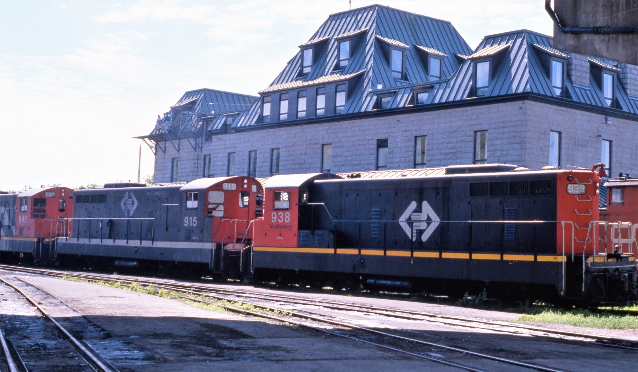 ON A WARM SUMMER'S EVENING. The lyrics from one of the late great Kenny Rogers biggest hits came to mind when the photographer captured three Terra Transport NF210's in the last days of their service on 'The Rock' on August 7, 1988. Parked on back of the Victorian Era Station that opened in 1903, the units are wearing three different paint schemes with the most rare being that of the 915. It was only one of two diesels painted as such with the formation of Terra Transport in 1979, the other being 917. The scheme was a throwback to the 1961 CN 'Noodle' era but a more modern version was later applied as seen on 938, with a much larger and centered TT bi-directional arrow, red on the cab sides and yellow safety stripes on the skirts. The 917 would later be repainted in that scheme with the 915 retaining her unique paint until the very end on September 30, 1988.By now train service was quickly winding down and a lot of motive power was being brought to St. John's for storage and eventual disposition.