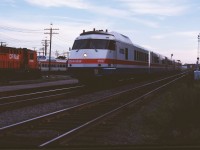 After early success with its French-built Turboliners, Amtrak ordered seven train sets based on the French design (but built by Rohr in California who had obtained a license from ANF. These trains used carbodies, wheels and engines brought from France while Rohr was responsible for the cabs and interiors. The trains were delivered in the second half of 1976 and assigned to "Empire State Service" in New York state, including runs to Montreal. In this photo we see nearly new car 159 leading the Adirondack past CP's Glen coach yard on the final lap of its trip from Grand Central station in New York to Windsor Station in Montreal. These train sets continued to serve Amtrak until the mid-1990s. The 159 was part of a group of cars removed from service for rebuilding in 1994 as the prototype for an "RTL II" modernization program. Alas, that was the only train set completed and it ran until 2002. (With supplemental information from Dale Johnson's book "Trail of the Turbo, The Amtrak Turboliner Story".)