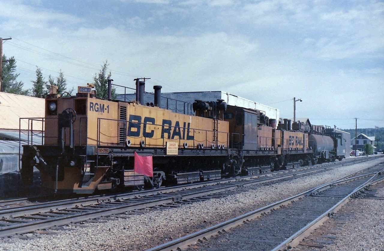 The picture was taken during the summer of 1988 and for some reason I can't find the exact date. The time of day would have been around 1800 hrs. The big surprise was finding the BCR rail grinder sitting on a siding near the station. It was shut down and the crew were out of site. I was told latter that the rail grinder was returned to the builder after CN took over & was scrapped. The van at the rear of the rail grinder is #1801 and the station can be seen on the right side of the picture.