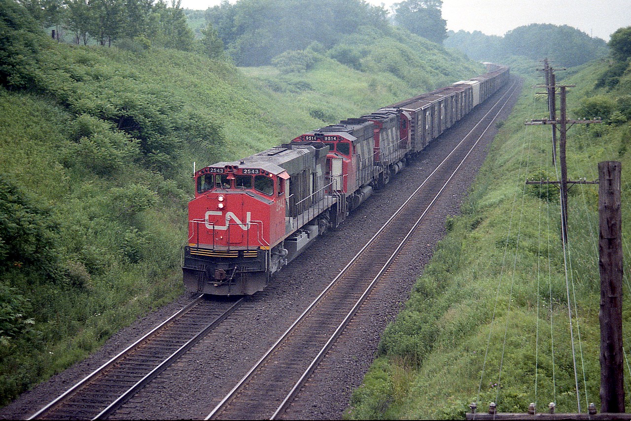 It looks a lot different looking eastward from the Inksetter Rd bridge at Copetown than it does now. This was a nice location that has gotten tighter with each passing year as foliage is allowed to creep ever closer over the RoW.
This image from back in 1984 has CN 2543, 9514 and 3208 up front of a westbound seemingly all boxcars. I rather miss them. It gets me to wondering what was in all those cars that we do not ship now.
The three locomotives featured are of course gone from the CN roster. CN 2543 was renumbered to 3543 and eventually ended up at Hudsons Bay Rwy. CN 9514 sold to Progressive Rail 2002; CN 3208 retired by 1989.