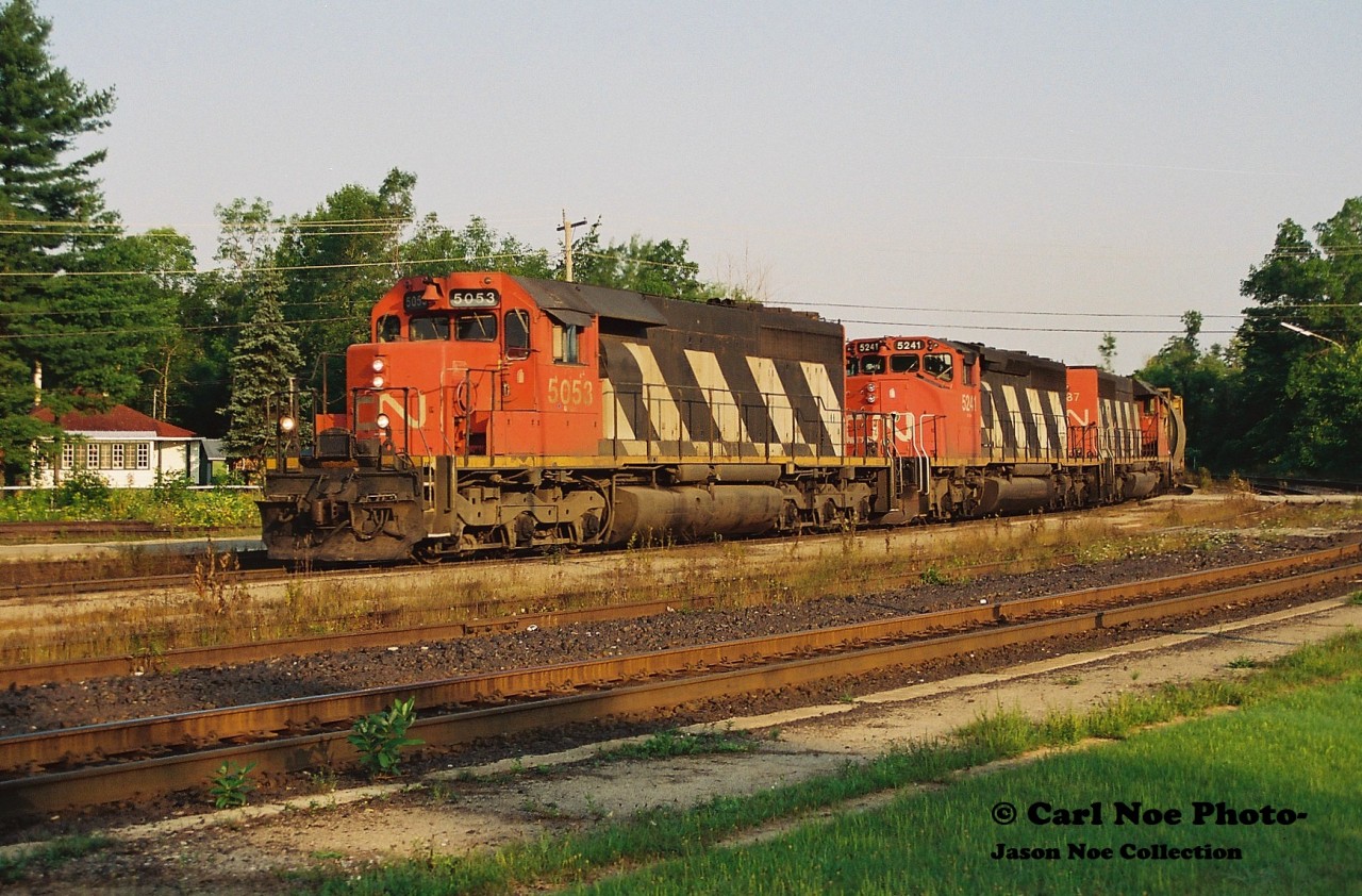 The early summer morning shadows have just receded far enough to allow for a view of CN Edmonton-Toronto train 304 curving through the village of Washago as it’s seen completing the final leg of its trip to MacMillan yard. Powering the southbound are CN 5053, 5241 and 5187.