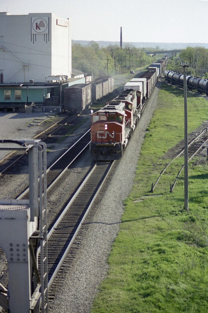 Here's a bit of a flashback.  Really nothing in this photo exists any more except the two main lines and the bridge in the background.
I am standing on the Waterdown bridge looking west, as a trio of GP40-2L (W) model locos come at me, led by CN 9584. On the left; the Kirkelder Spray Mister building, later Aldershot Cold Storage, was razed in 2009. The siding where the boxcars are seen is now 3rd track to accommodate Metrolinx. Chimney in distance was part of Burlington Brick Co., now cleared out and a new survey of homes on the site. On the right, the stub with the tank cars on it is gone, and now there is a two track lead to the Aldershot Yard over this ground. The Lemonville Rd bridge in the background is still there, and is still used by fans on occasion for photography.
For anyone who wants to brave the traffic on the Waterdown bridge, an interesting "time machine" photo could be had here.  I'm wondering abut the car on the left side .... it has to be a railfan, but who?
