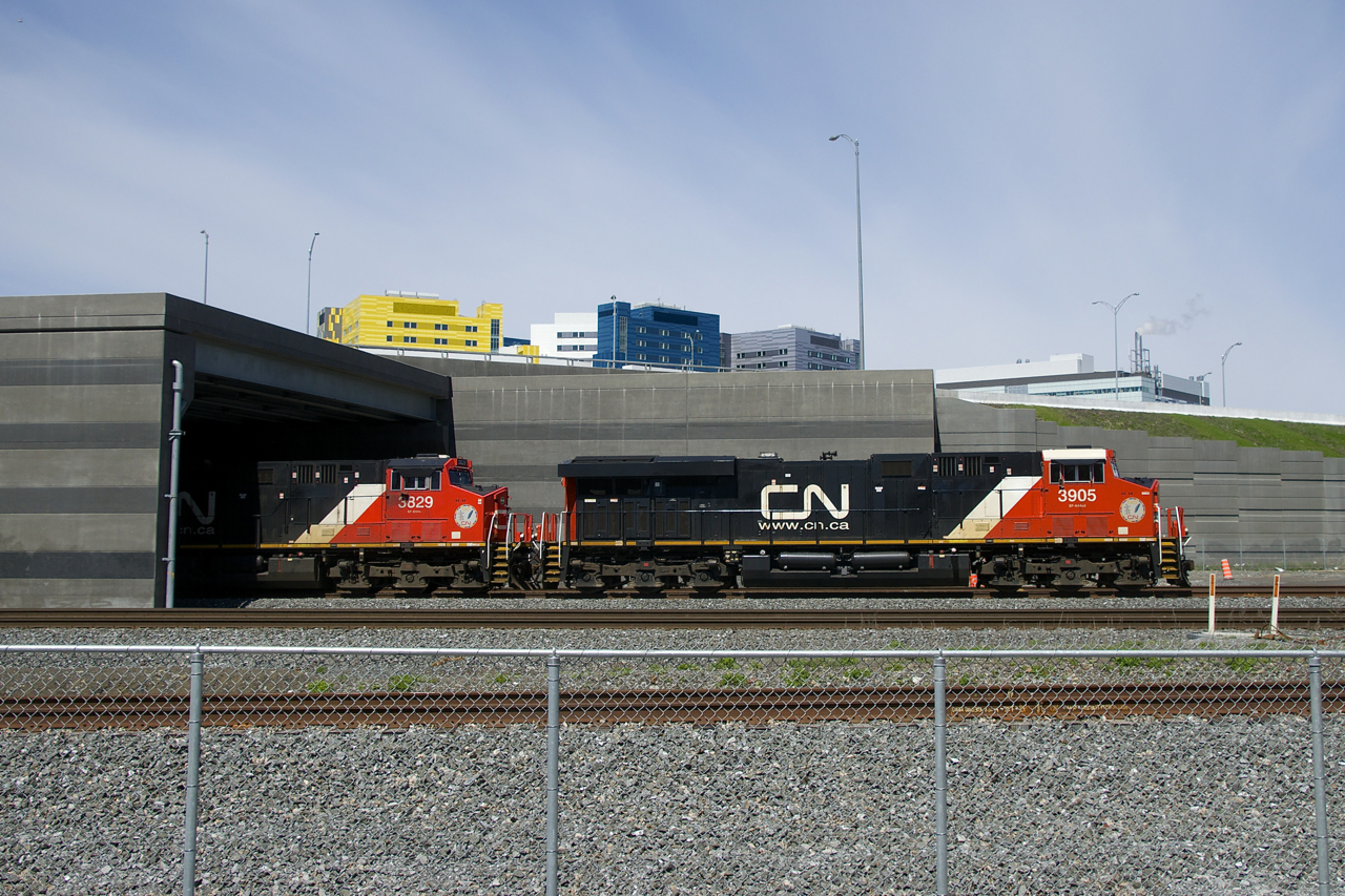 CN 120 is emerging from a tunnel under the newly rebuilt Turcot interchange as it heads east on the freight track of the Montreal Sub. Up above is the McGill University Health Centre, which is located on the site of CP's Glen Yard.