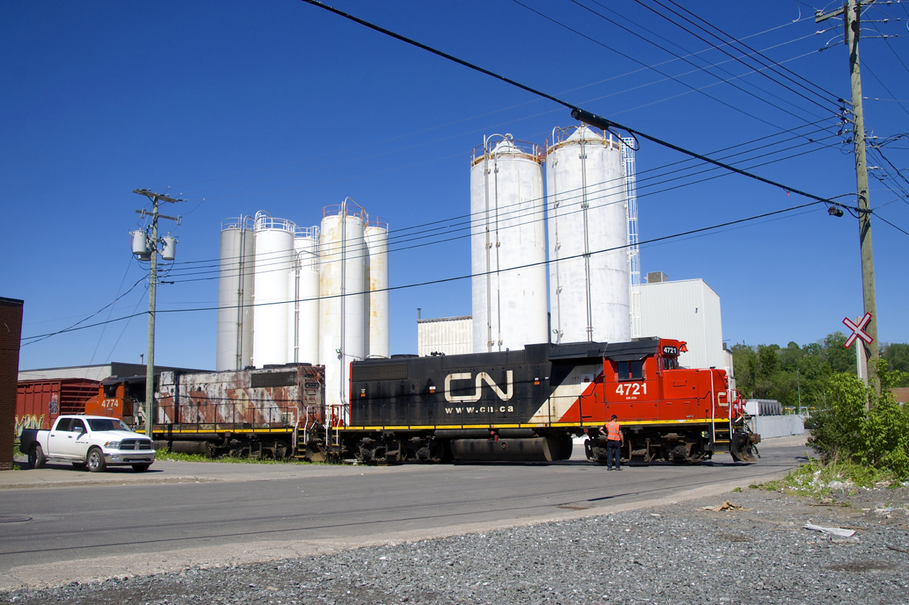 A conductor is finishing flagging Place Turcot as the Pointe St-Charles Switcher leaves the Kruger plant with CN 4721 & CN 4774 for power.