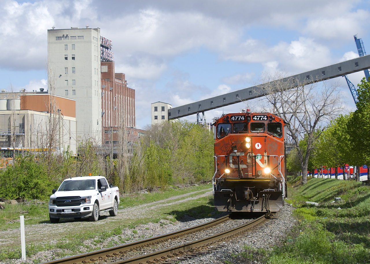The Pointe St-Charles Switcher has left the Port of Montreal and is heading back to its namesake yard with four cars as it passes a foreman. Where the foreman is parked once had a couple of tracks that were used for runaround moves.