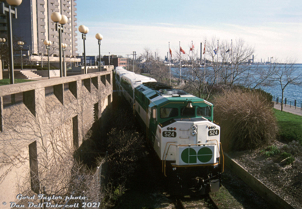 GO trains in Sarnia? The new CN St. Clair Tunnel opening between Sarnia and Port Huron on May 5th 1995 featured a few special events held on May 5-7th to celebrate this cross-border rail connection under the St. Clair River. According to a 1995 issue of Branchline, a few special trains were run from Toronto and the US to the event. VIA and GO Transit equipment was borrowed for some of those specials, and another GO consist was used as a shuttle train giving rides through the tunnel for the event (there were some customs checks needed for riders). Officials and dignitaries had their event on Friday the 5th, on the 6th was for employees, and the 7th was for the general public.  On May 6th, the employee event, three special trains were run to Sarnia's Centennial Park on the waterfront (via the Point Edward Spur) for the opening day events. Two consists ran from Toronto (VIA F40's and LRC cars for one, and a double-ended GO consist for the other) and a special from the US with GTW and Amtrak equipment all headed down the Point Edward Spur, where they laid over near the park, from which they would depart from at the end of the celebrations. Shown here, GO F59PH 524 passes by the First Sarnia Place parking garage on the waterfront at Front & Lochiel, as it brings up the rear end of one of the employee specials from Toronto, an L7L consist with 524 on one end and 544 leading on the other. It's likely the end of the day and the train is returning back to the mainline to return to Toronto after the end of celebrations. The GO tunnel shuttle ran with different borrowed GO equipment through the tunnel (568 at one end and a cab car at the other).  Gord Taylor photo, Dan Dell'Unto collection slide.