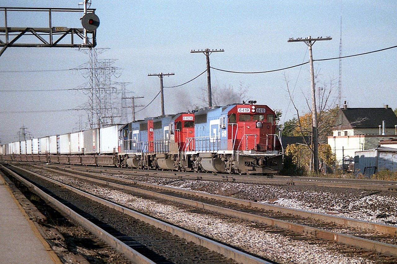 This photo is from around the height of excitement for the fans regarding CNs "Laser" service run thru power. It was prevalent on most of the daily trains #238 (Chicago-Montreal) and return #239. Not often would I catch the train with 3 Grand Trunks. Sometimes it was just two units, sometimes a DT&I mixed in, sometimes CN mixed in; you just never knew.
The "Laser" was not an extra fast train, but just a catchy moniker for CN's TOFC (trailer on flat car) service using well cars in order the trains utilize the rather restrictive Port Huron-Sarnia tunnel under the St. Clair River.
This operation started around 1982 and by 1992 CN had graduated to using containers, and with the later enlarging of the tunnel, double stacks. Containers proved much more efficient that moving truck trailers by rail. Power on this train, which is just hitting the CN Halton sub off of the Oakville, is GT 6419, 6405 and 6415.