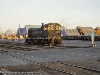 With just a hint of evening glow, Vancouver Wharves 24, a former CNR S2, putters its way along the waterfront passing some of the many rail served industries.  The unit was built by MLW in <a href=http://www.trainweb.org/oldtimetrains/photos/cnr_diesel/8141.jpg>June 1949 as CNR 8141,</a> and was the last S2 CNR would receive.  It was retired in 1973 and sold to Vancouver Wharves.  Photos show the unit operating into at least 1978, disposition unknown.<br><br>Those familiar with the Ontario Southland Railway roster will know there are two former Vancouver Wharves units that made their way to Oxford County.  <a href=http://www.railpictures.ca/?attachment_id=6096>OSRX 500,</a> a 1956 ALCO S6 built for the Southern Pacific was <a href=http://www.trainweb.org/oldtimetrains/industrial/bc/VW_29.jpg>Vancouver Wharves 29,</a> and <a href=http://www.railpictures.ca/?attachment_id=18818>OSRX 502,</a> a 1959 MLW S13 from the Pacific Great Eastern Railway, operated as <a href=http://www.trainweb.org/oldtimetrains/industrial/bc/VW_827.jpg>Vancouver Wharves 827.</a>  The 502 was sold along with OSR 501 to the Waterloo Central Railway in 2018, now appearing as <a href=https://1.bp.blogspot.com/-JNj-ebYS1gk/X0fLGsJqWgI/AAAAAAAAZkI/c3pgmDwA5scdSriHOL3in56YvcOG-AVYACLcBGAsYHQ/s1600/0Q0A3281_resize.jpg>WCR 1001 and 1002.</a><br><br><i>Bryce Lee Photo, Jacob Patterson Collection Slide.  Geotagged location not exact.</i>