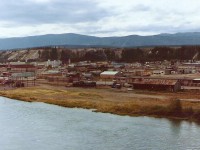 To get this picture I had walk up a gravel road on opposite of the Yukon river. The camera location allowed me to look down into Whitehorse. The two stall engine house is easy to see and in front of it you can see a pair of locomotives (WP&Y 90 & 91) along with van #901. The side of the engine house looks black which it was at the time. A few years earlier two river boats had burned to the ground near the building & the heat from the fire 
allowed the stone granules to fall off the siding and leave a dull black surface. Also you can see a flat area between the shop area and the Yukon river. That was the site of the BYN CO. Whitehorse shipyards a subsidiary of the WP&Y.  The engine house has been relocated and there is almost no existing evidence that a railway existed in the area.