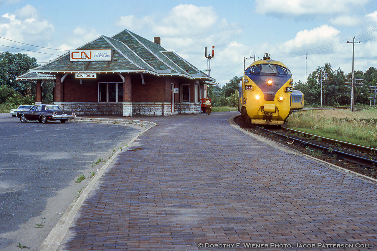 The fourth and final TEE trainset purchased by the Ontario government for use on the Ontario Northland Railway’s Northlander operation is seen making its southbound station stop at the 1917 Orilla station headed for Toronto.Less than a year since arrival on Canadian soil, the 4 sets arrived originally numbered 1900 – 1903 and were renumbered to 1980 – 1983 soon after.  With the retirement of the European power cars due to poor performance in harsh Canadian temperatures in 1979 and replaced by modified F-units, they would again be renumbered to 1984 – 1987 and the sets finally retired in the early 1990s.  Some cars were sent back to Europe for display in a museum, while a couple still remain on the ground in a fenced lot in North Bay.Since the removal of the tracks in 1996, the station, owned by the city, has continued to serve as a stop for Ontario Northland buses, a Service Ontario office, and other small operations until April 8, 2019 when the property was purchased by a numbered company.  The city had attempted to sell the property a few years earlier but paused the sale until the structure could be designated a protected heritage site.  A partner of the company, Eric Pong,  recently announced the intentions of the owners to use the building as an art gallery and museum focusing on the heritage of the site and Orillia’s railways.More Orillia:Eastbound Canadian, April 1979 by Barry Schroeder.Hooping orders to the westbound Canadian, June 1980 by Steve Danko.Dorothy F. Wiener Photo, Jacob Patterson Collection Slide.
