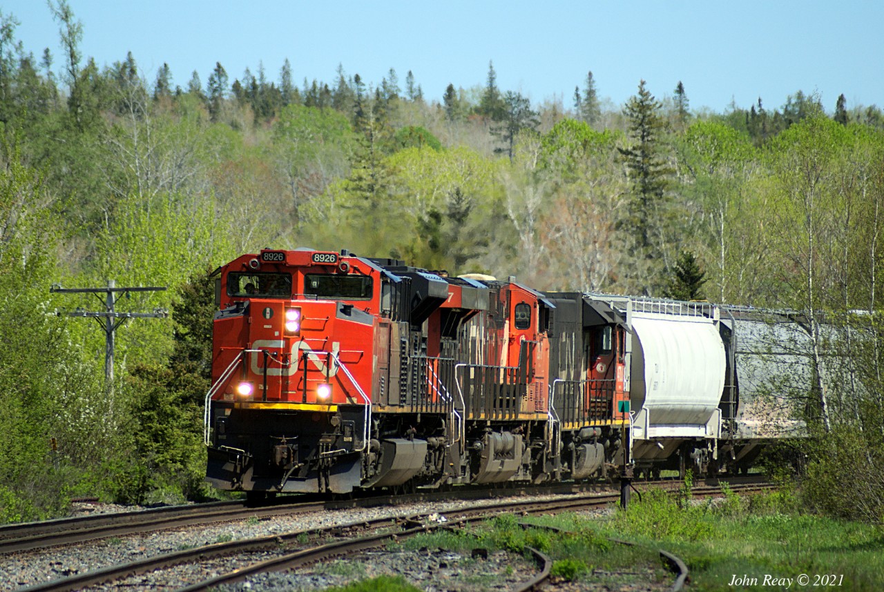 CN train 407 approaching Oxford Jct, MP 46.7 CN Springhill sub at 15:29 on May 24th, 2021, with the station sign in view. This train had 296 axles and three units (trailing unit is CN 4700, a conventional cab GP38-2, possibly heading to Moncton for service.)