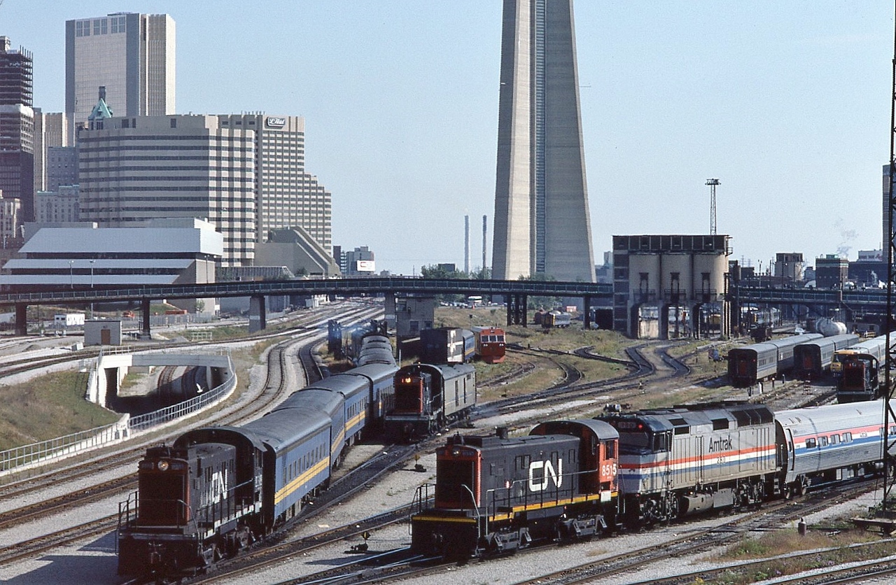 Busy Sunday afternoon at Spadina,

 
  Entertainment provided the S-13's, a plenty...

 
  CN 8518 pushing a string of blue coaches through the wash and another S-13 has a Tempo generator – baggage in tow...

 
   and 8515 is working the AMTRAK F40PHR #280 with the Maple Leaf consist 

 
  CN Spadina coach yard, September 30, 1984 Kodachrome by S.Danko

 
   Noteworthy: from the right, in the coach yard, two more S-13's,  LRC cars, Tempo cars, in the distance Budd Cars, what appears to be a Track Inspection Car or Rail Grinder, a regular tail end feature of the seventies Super Continental: CN 'car-go-rail'  enclosed auto carrier, and the nearly new rail grade separation line.