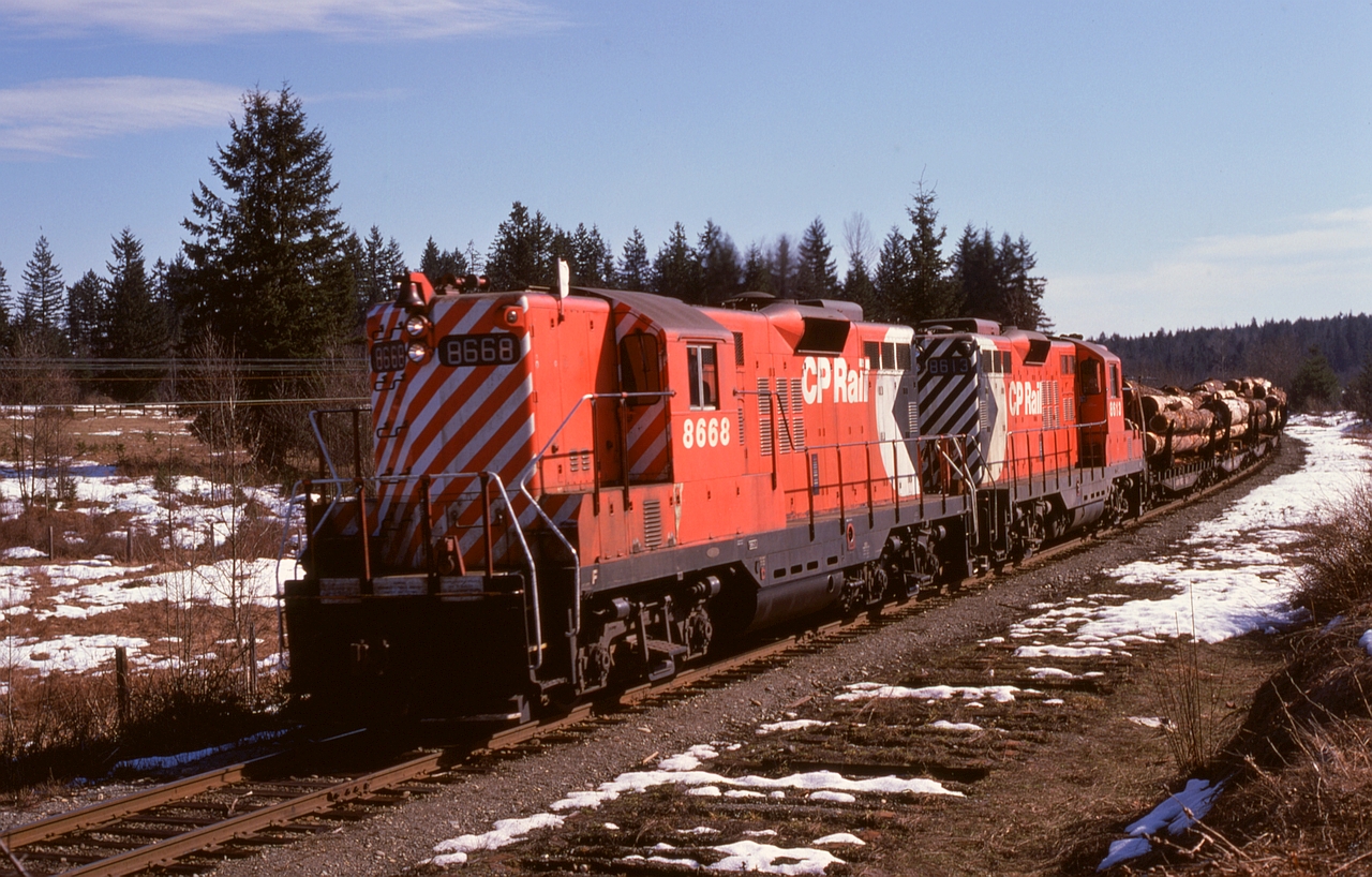 Saltair at mileage 54.5 on CP’s E&N Victoria subdivision on Vancouver Island, midway between Chemainus and Ladysmith, had a 24-car siding on the west side up to and including timetable 96 of 1971-04-25, but timetable 97 of 1971-10-31 showed it as “nil” and Saltair disappeared from record in timetable 92 of 1973-10-28.  A few years later, clear evidence of the siding remained as a Nitinat log train (Crown Zellerbach loads from Lake Cowichan to Ladysmith) with GP9s 8668 and 8613 headed north on Friday 1975-03-07.