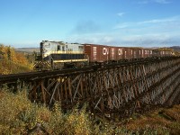 <p>Eastward from Dawson Creek, BC, on Northern Alberta Railways, there were two large timber trestles, first at mileage 134.7 over Dawson Creek east of Iracard and second at mileage 131.5 over Bissette Creek just east of Pouce Coupé.  This is the long one over Dawson Creek and just 3.3 miles east of the town, built in 1951 to replace a challenged one a few hundred feet downstream (to the right), here carrying timetable train No. 52 (a Tuesday, Thursday, Saturday wayfreight returning to Grande Prairie, AB) on Tuesday 1977-09-20 with GP9 210 and thirteen cars plus caboose.</p>

<p>A similar shot, but taken three years later from an elevated viewpoint up a tree, is on the back cover of the recent NAR Diesels book by Les Kozma.</p>