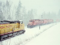 Before purchasing any AC-drive locomotive (other than pioneer M640 4744), CP assessed what high-powered DC units were on the market by borrowing from other railways, and in the winter of 1990-1991 tested a near-new trio of Union Pacific GE Dash8-41CW units on grain trains between Calgary and Vancouver terminals, seen here as UP 9416+9413+9409 on 1991-03-03 with westbound loads in the siding at the west switch of Yale, BC, at 1531 PST in a snowstorm, meeting an eastbound with three SD40-2s CP 5861+5666+5676 and grain empties.  PK okay, have a good trip.