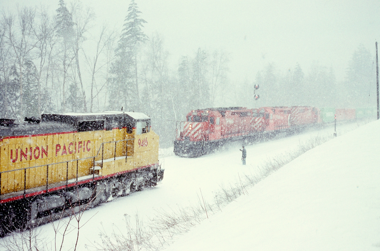 Before purchasing any AC-drive locomotive (other than pioneer M640 4744), CP assessed what high-powered DC units were on the market by borrowing from other railways, and in the winter of 1990-1991 tested a near-new trio of Union Pacific GE Dash8-41CW units on grain trains between Calgary and Vancouver terminals, seen here as UP 9416+9413+9409 on 1991-03-03 with westbound loads in the siding at the west switch of Yale, BC, at 1531 PST in a snowstorm, meeting an eastbound with three SD40-2s CP 5861+5666+5676 and grain empties.  PK okay, have a good trip.