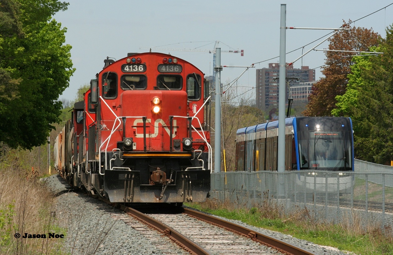 CN L568 with 4136 slowly shoves toward downtown Kitchener on the Huron Park Spur as an ION light rail movement heads the opposite direction approaching Mill Station at Ottawa Street.