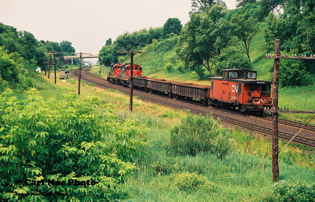 CN "Triple 5" heads westbound up the grade through Copetown under the watchful eye of a foreman as it proceeds to Paris with cars for the busy pit. Matching CN GP9RM's 7042 and 7028 are powering the Hamilton-based local with CN van 79752 on the tail-end.