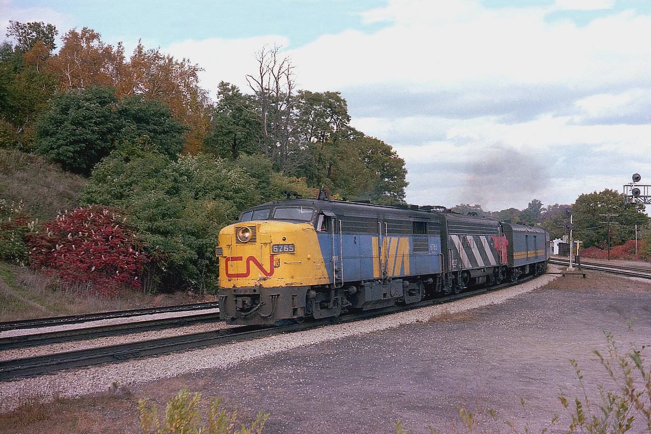 It is a pity a cloud bank arrived to somewhat put a damper on the scene, but it still is a nice picture. The "CN" on the nose of the early VIA engines was not all that common, and only at the start up was this applied.
And does look rather nice.
We are at Bayview Jct as the 'noonish' train #73 swings off the Oakville sub on its way westward. The other engine is CN 6527.  The 6765 is preserved at the rail museum near Delson, Quebec.
This image was shot with 35MM Sakuracolor film using a Pentax K-1000. (the old reliable)