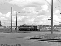 Sitting in suburban Scarborough at the border between industrial areas and residential neighbourhoods, Canadian Pacific RS3 8445 awaits its next duties switching the Scarborough Industrial Spur, on one of the leads near the Ashtonbee Team Tracks at Bertrand Avenue and Thermos Road. The single-level suburban houses visible in the background are located off Birchmount Road, and the large factory in the background is the Federated Metals plant.<br><br>The Scarborough Industrial Spur was built in the early 1950's to serve the industrial post-war boom in the "Golden Mile" area of Scarborough, one of the fast-growing inner suburbs surrounding the old city of Toronto proper. It branched off CP's Belleville Sub at Mile 201.36, crossed Warden, and ran south parallel to Warden and Birchmount (serving a few businesses that sprung up along Howden Rd enroute) to reach industries in the Golden Mile north of Eglinton Avenue East, which included Volkswagen of Canada, Link-Belt, Canadian General Thermos, Kaiser Aluminum, and Canadian General Electric's Scarborough plant (formerly English Electric / Inglis). There was also a branch that ran up Underwriters Road, and a few sidings and ramp for a team track at Ashtonee Road (see 1957 CofT aerials <a href=http://jpeg2000.eloquent-systems.com/toronto.html?image=ser12/s0012_fl1957_it0071.jp2><b>here</b></a> and <a href=http://jpeg2000.eloquent-systems.com/toronto.html?image=ser12/s0012_fl1957_it0090.jp2><b>here</b></a>). The Golden Mile industries on the south side of Eglinton were served by CN via their <a href=http://www.railpictures.ca/?attachment_id=34884><b>"GECO branch"</b></a>. <br><br> CP's Scarborough Industrial Spur was eventually abandoned in the mid-90's as all the old heavy manufacturing industry left the area or switched from rail to truck, and urban redevelopment and gentrification of the area started to set in (the Golden Mile strip of Eglinton today features power centers, car dealerships and big box plazas mixed in with repurposed industrial buildings and some remaining legacy industry, and the Eglinton Crosstown LRT line will bring more changes when completed in the future).<br><br><i>Original photographer unknown, Dan Dell'Unto collection negative (large-format scanned with a DSLR, with some restoration work done).</i>