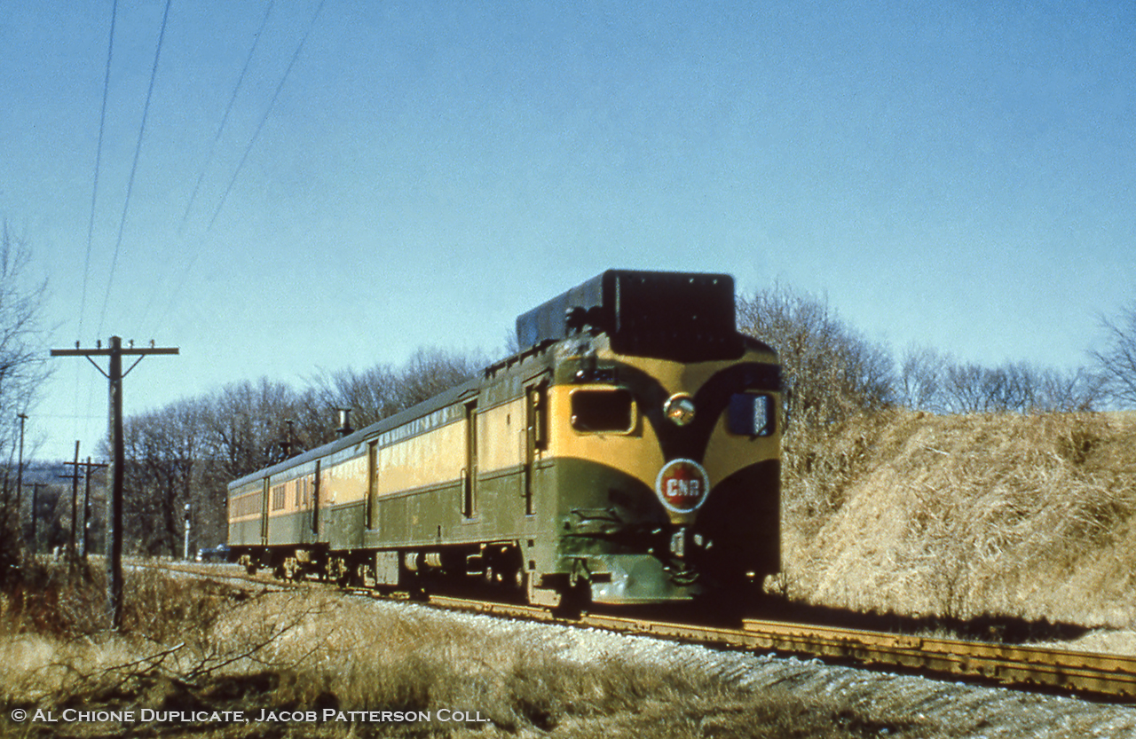 Seen in it's original paint scheme (post 1951-52 rebuild from CNR 15834), CNR D-1 and trailers C-1, C-2 roll along the Milton Sub near Burlington, likely having just crossed old Highway 25 (note wig wags and traffic in the distance).  Within the year, D-1 would receive a new paint job as seen in this 1958 photo, as well as an additional window at the centre of the cab, and new headlights.  Note the early version of the CNR maple leaf logo.  Images of this scheme an logo can be found back to 1948, though the year of introduction remains unknown.  Anyone?This location proved a challenge to find, as the slide was simply marked "near Hamilton."  After looking over 1954 air photo of Southern Ontario, and comparing this to google maps, sun angles, and with a 1956 timetable I believe the location to be along the Milton Sub (single track) and between the curve near the Guelph Line crossing and the curve at Walkers Line.  The 1954 aerial shows little foliage around the crossing though, which leaves one location, a crossing, now long gone, just east of Guelph Line that would be located roughly where the Burlington Leon's is located.  The 1954 aerial labels it as Highway 25, though today that would be farther east from here, presumably relocated/renumbered over time.  The return trip at this location would be under the cover of darkness, making this the morning trip, train 660 to Georgetown.  Further train numbering information under 1958 photo linked above.More CNR green and GOLD, 1952 by Bill Thomson at Toronto.Original Photographer Unknown, Al Chione Duplicate, Jacob Patterson Collection.  Geotagged location not exact.