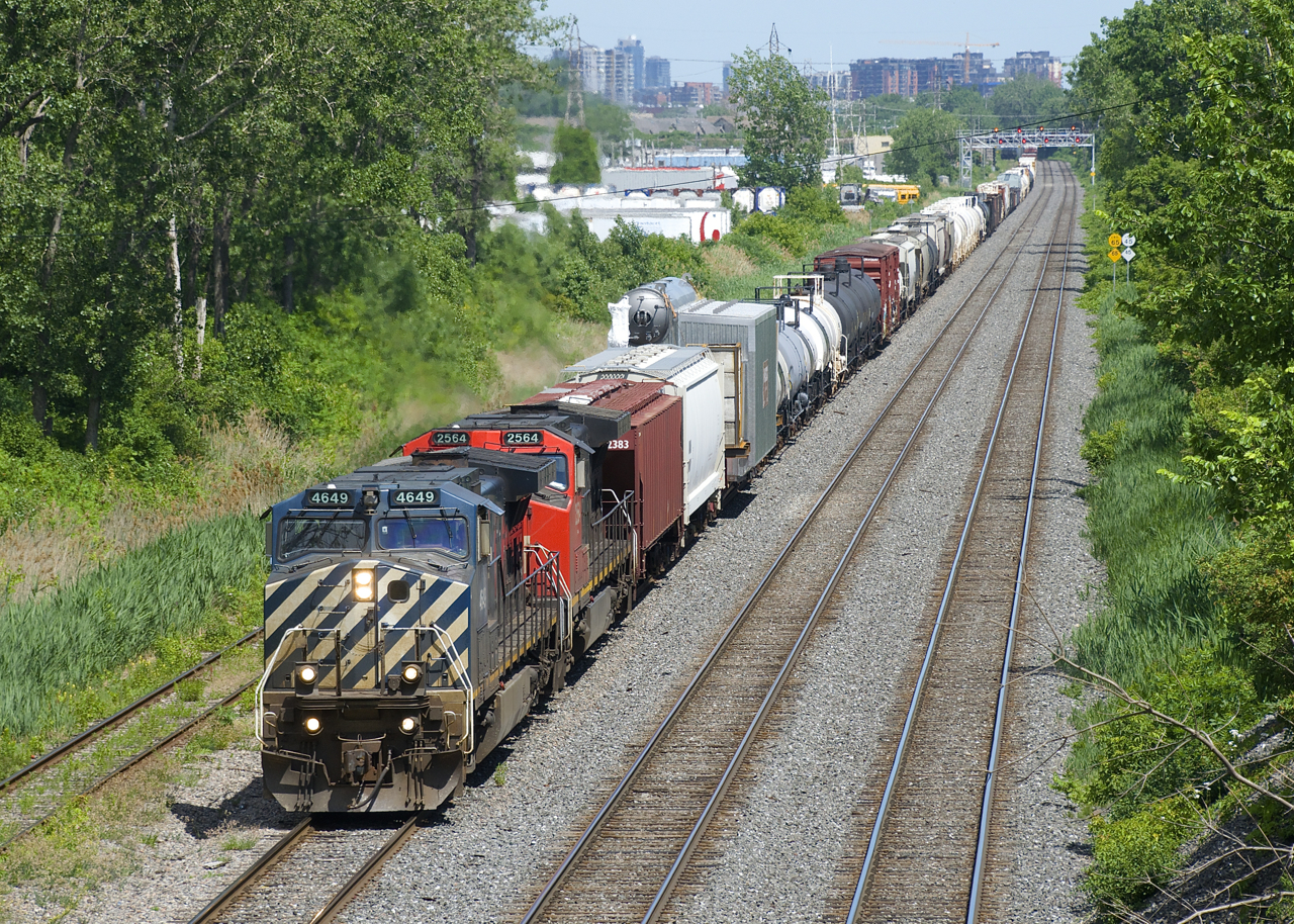 CN 527 has a long train and Dash9's in two paint schemes (BCOL 4649 & CN 2564) as it slowly approaches Taschereau Yard with a long train. It will have to cool its heels a bit before being getting its signal to enter the yard. The third car is a large boiler from Indeck in St-Hyacinthe.
